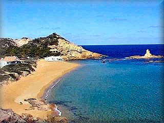 La hermosa y por eso famosa playa de cala Pregonda con sus rocas en la bocana que la ocultan de la mirada desde el mar le dan un alo de misterio, su arena es finicima y dorada 