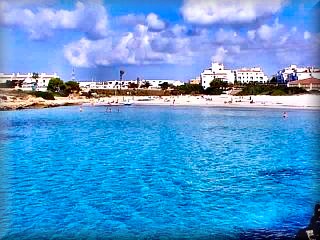 Calan Bosch vista panoramica de la playa con la urbanizacion al fondo, las bancas arenas y el azul del agua invitan al ba&ntilde;o y tomar el sol